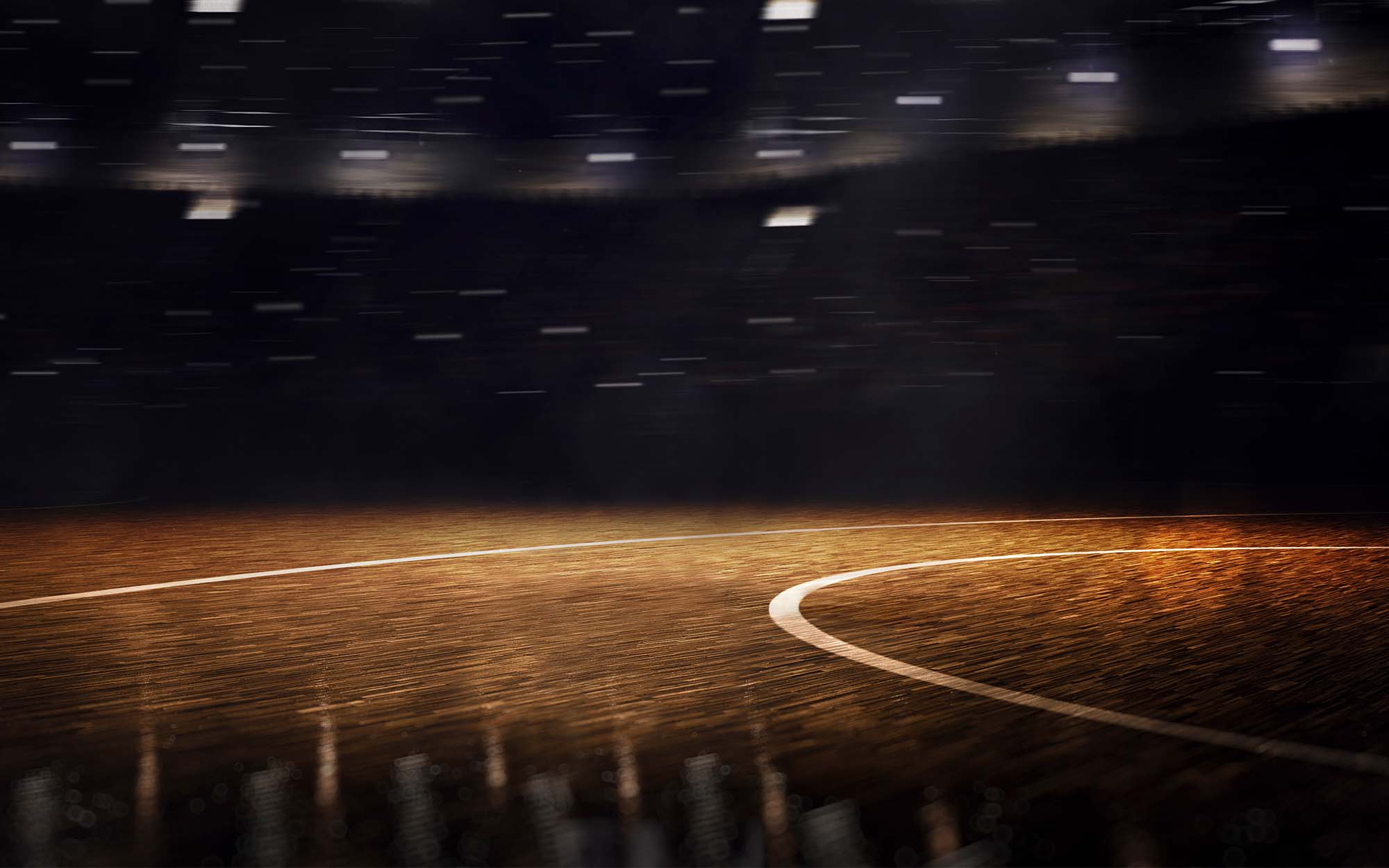 A dramatic indoor basketball arena in the United States with the hardwood court lit for a game