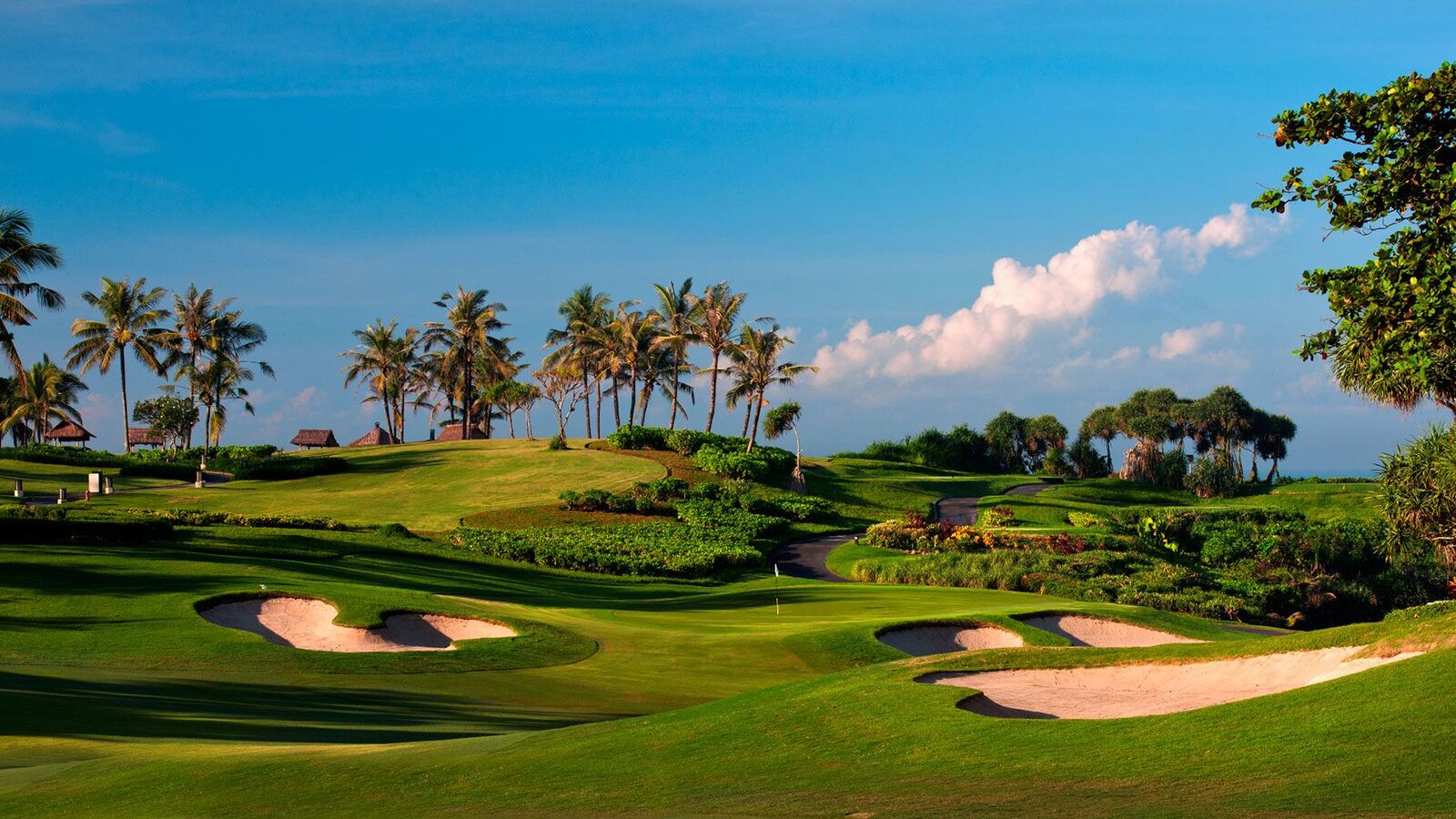 A stunning tropical coastal golf course with fairways running alongside the ocean, representing international golf tours in Asia