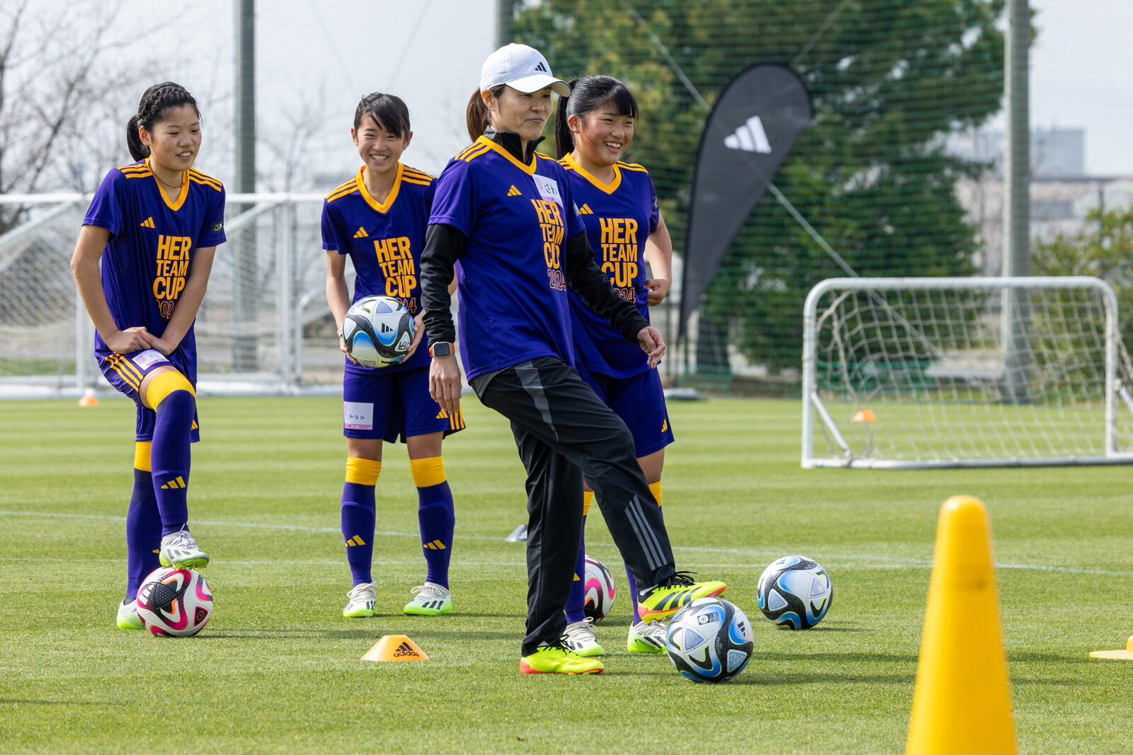 Young footballers training with a coach on a pitch in Japan ahead of a youth tournament in the Kansai region