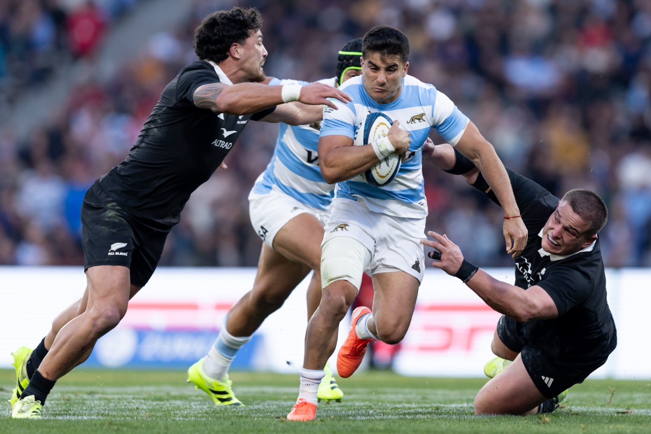 Argentina Los Pumas rugby player carrying the ball while being tackled by opposing defenders in an intense international contest