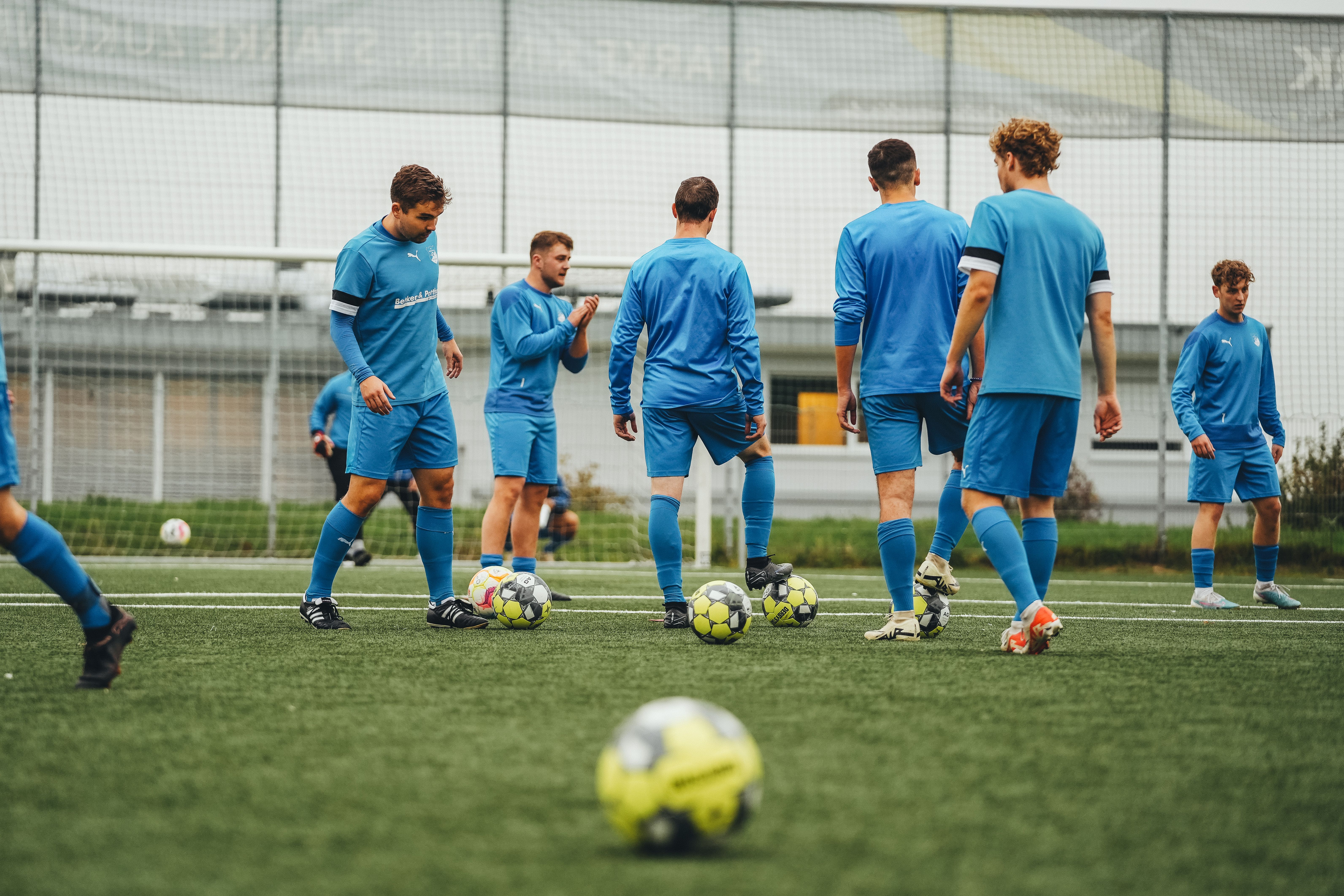 A football squad training together with the ball on an outdoor pitch during a high-performance team tour
