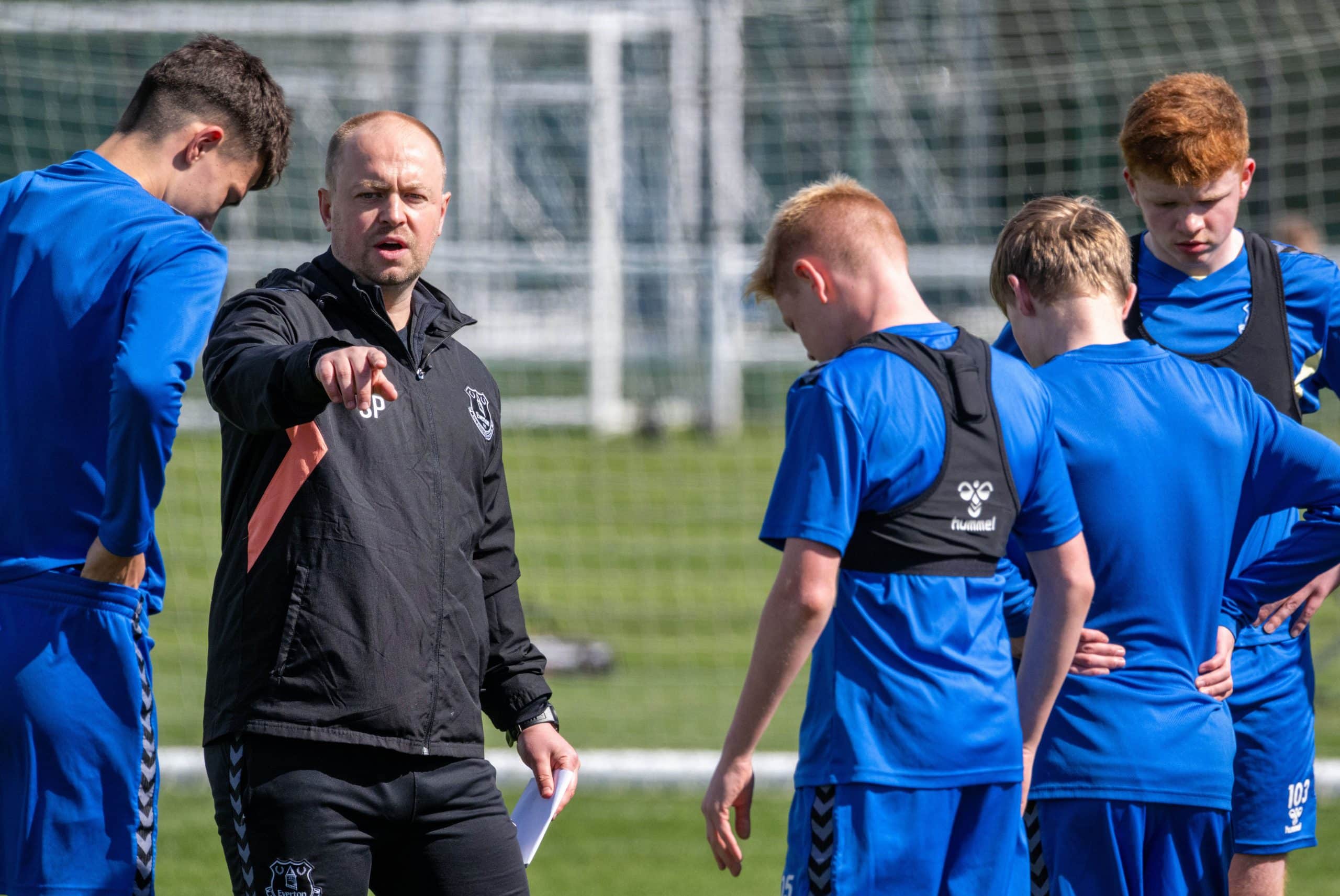 Young footballers training with a coach on a UK pitch ahead of a youth football tournament