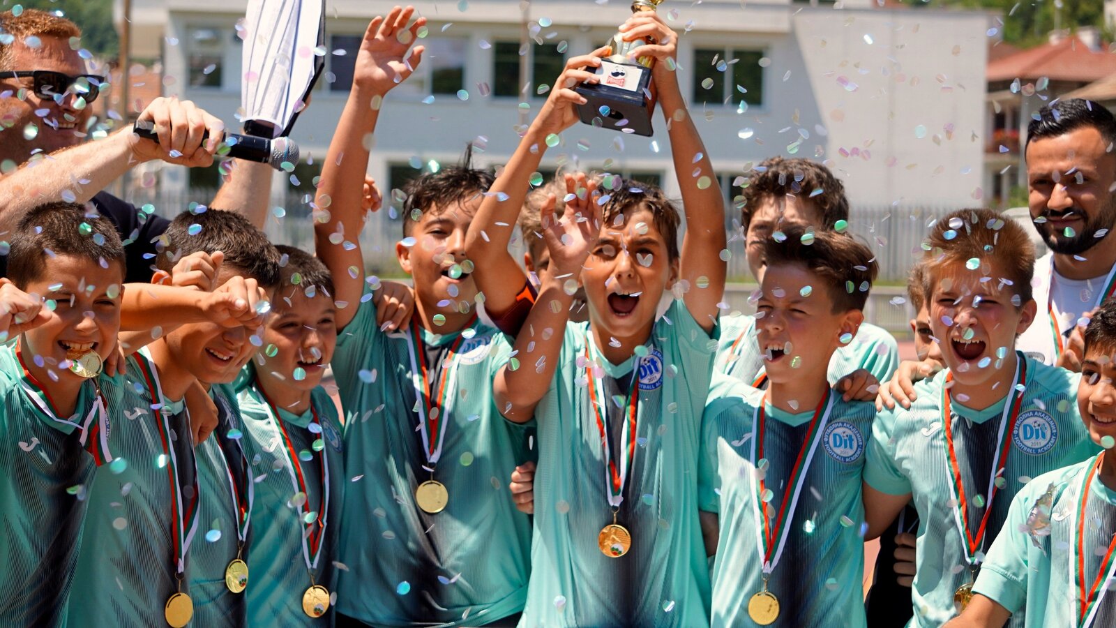 Youth sports team celebrating together with a trophy and medals