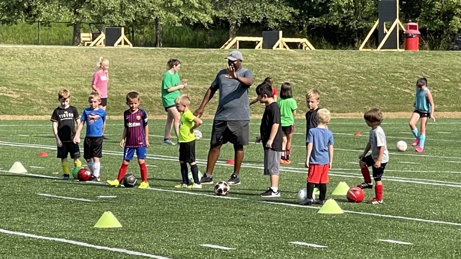 Youth football team training with a coach on an outdoor pitch