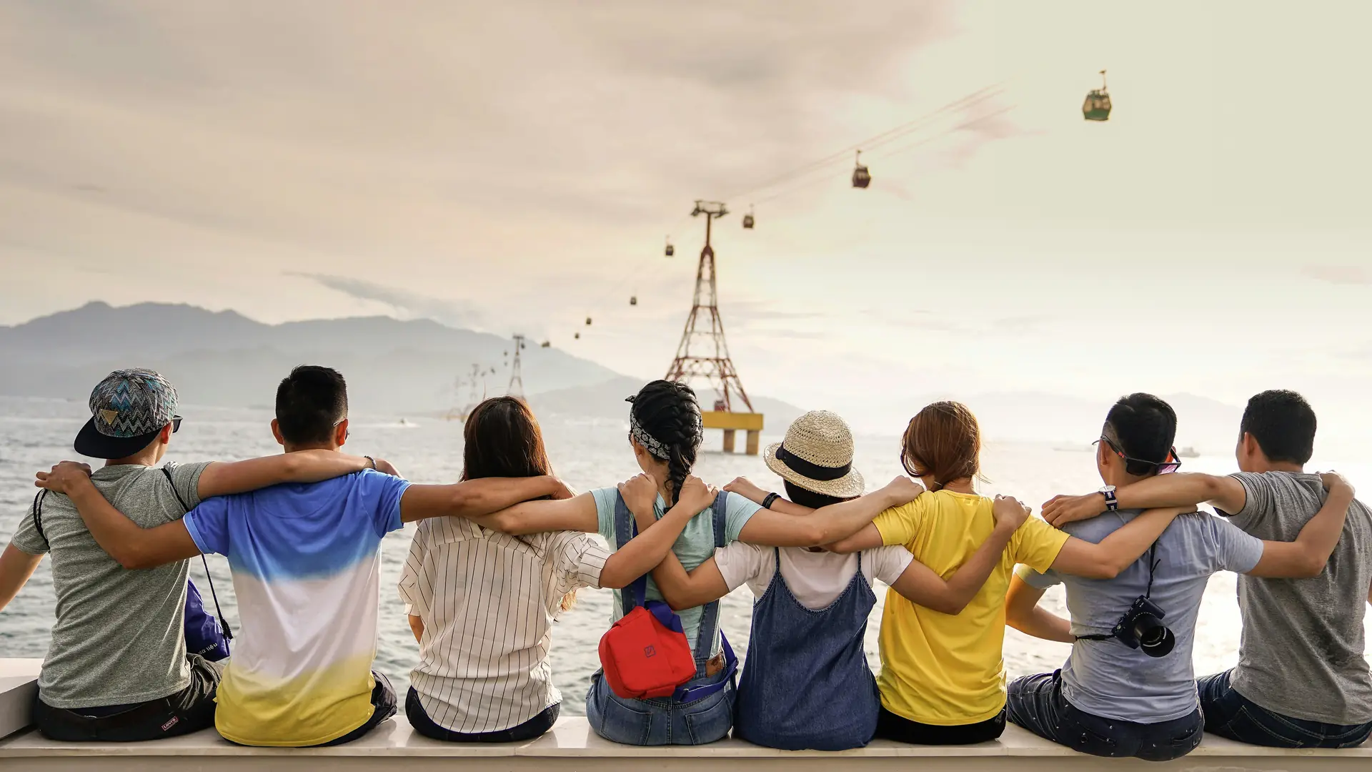 A group of young people sitting arm in arm by the sea