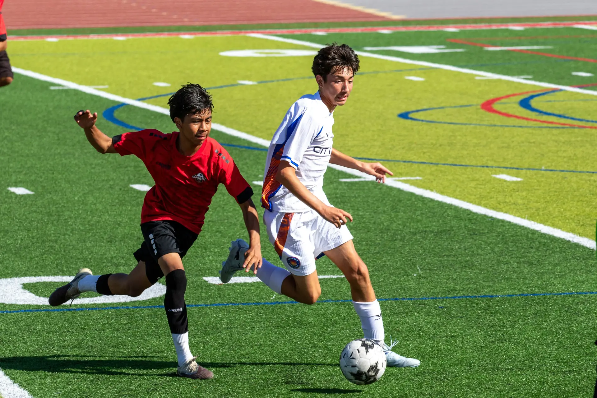 Two young footballers chasing the ball during a match