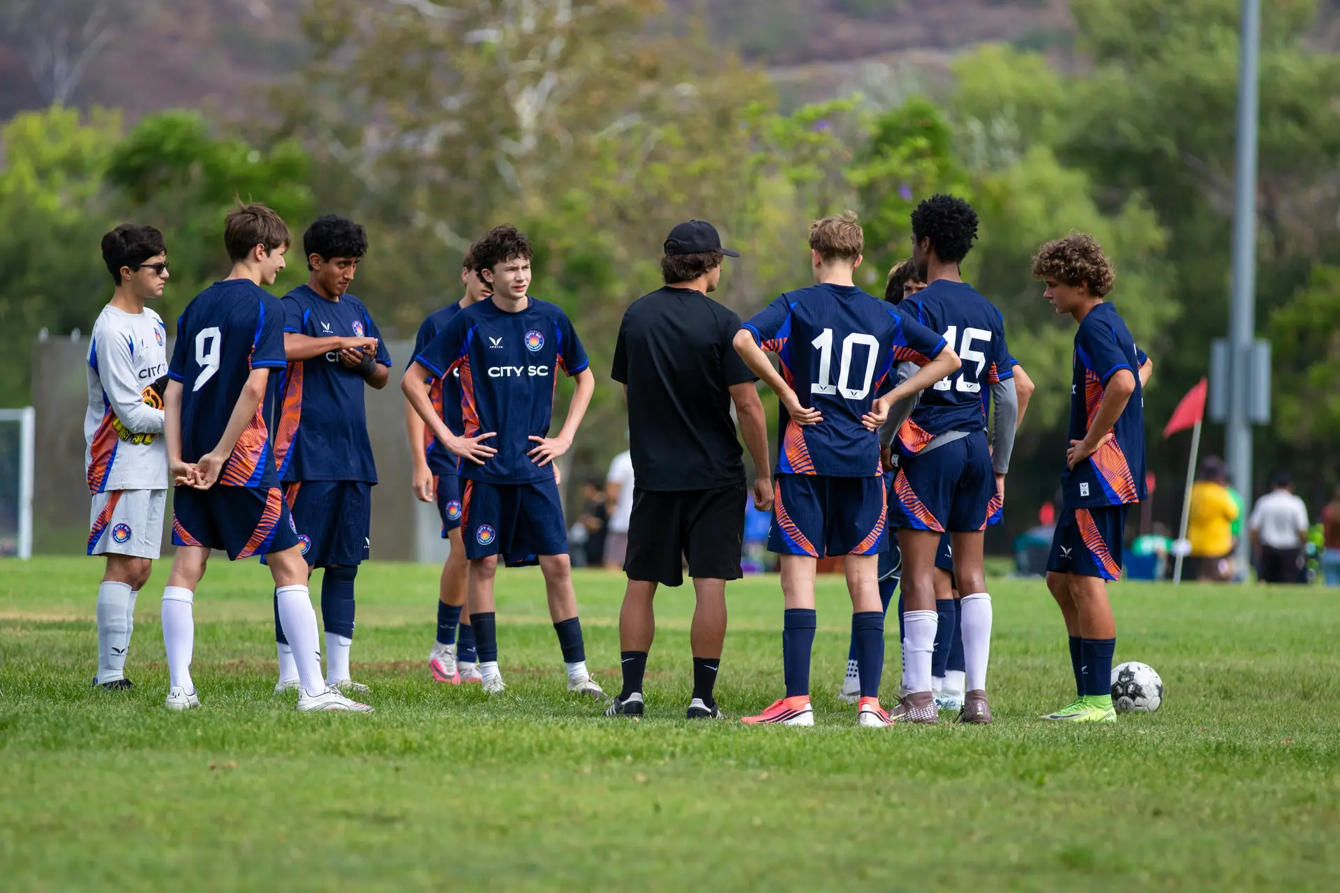 A coach talking to a youth football team on the pitch