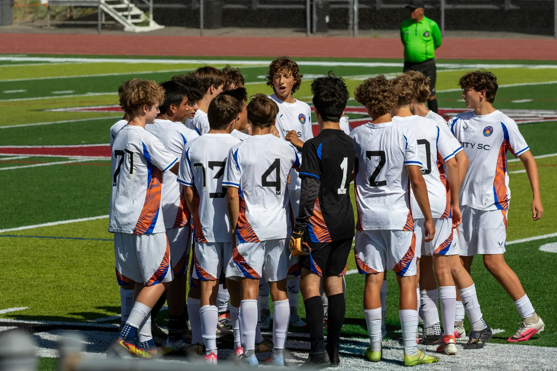 A youth football team gathered together on a sunny pitch