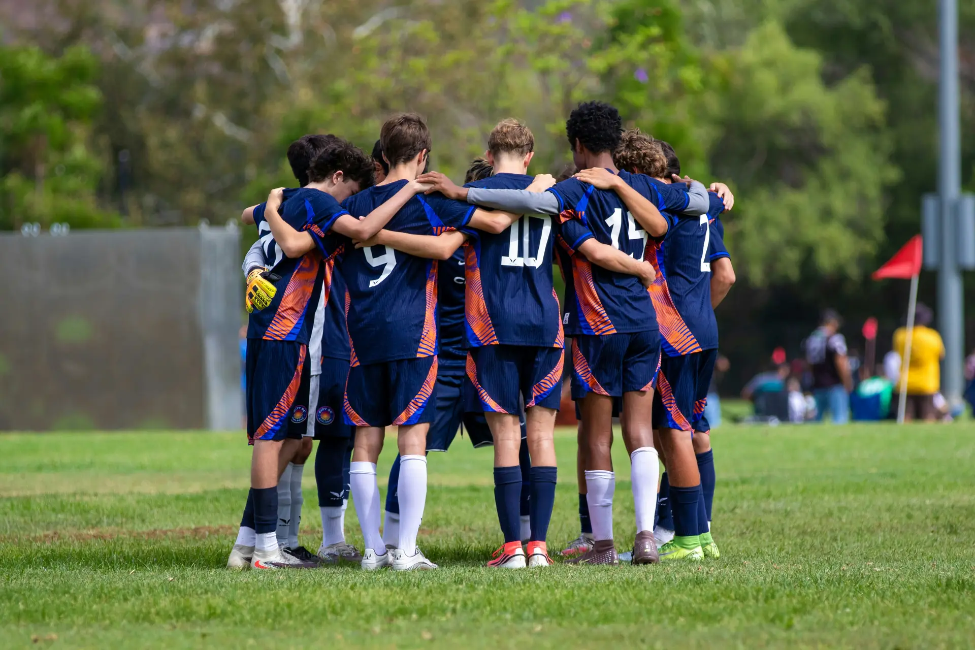 A youth football team in a huddle on the pitch