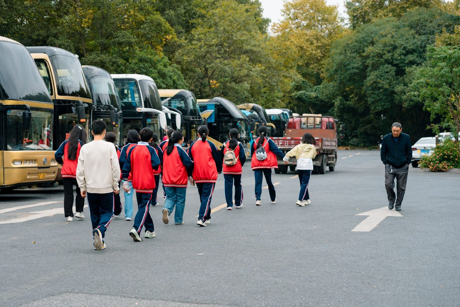 A school group in sports tracksuits walking to their coaches.