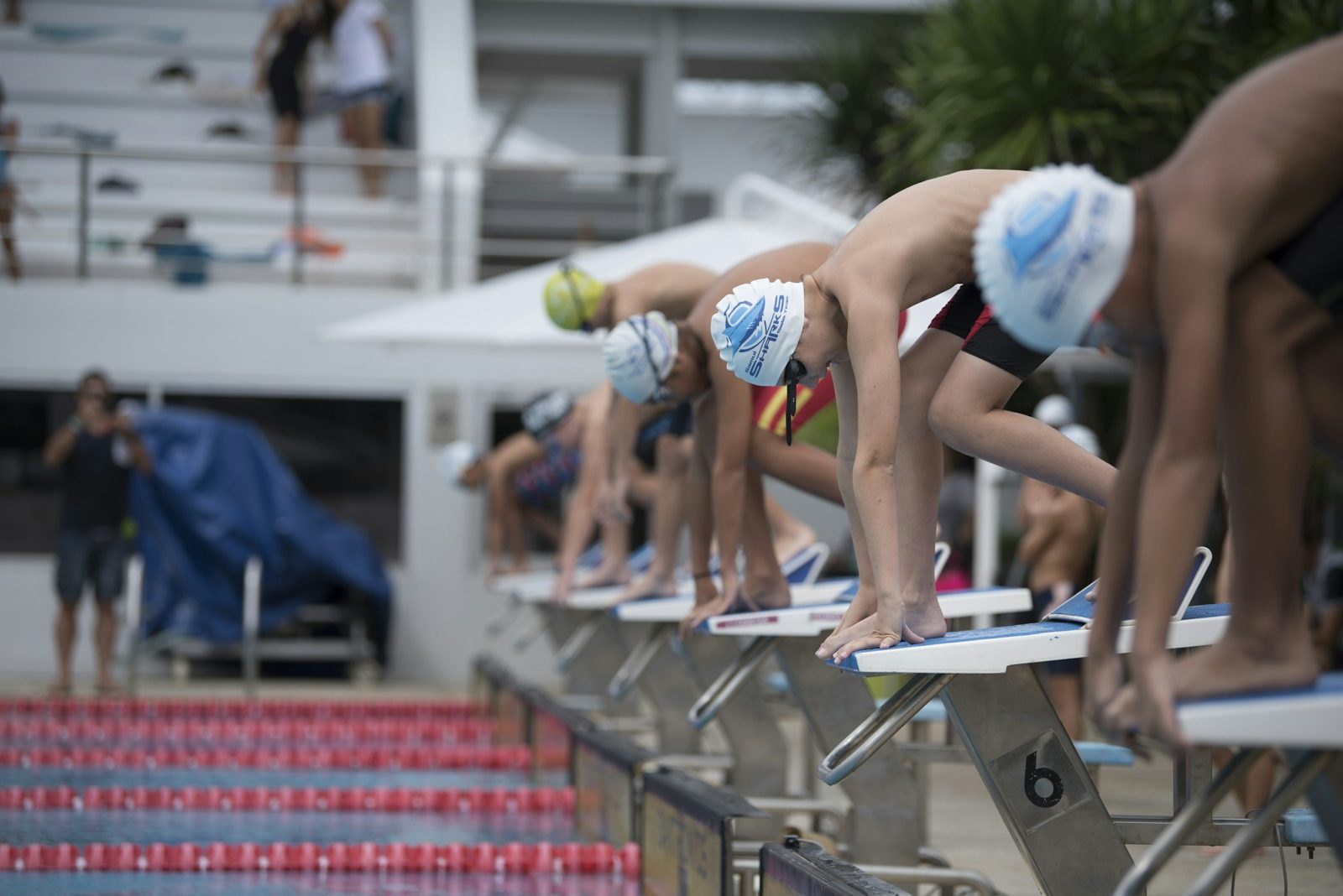 Junior swimmers on the starting blocks at an outdoor pool in Phuket, Thailand.