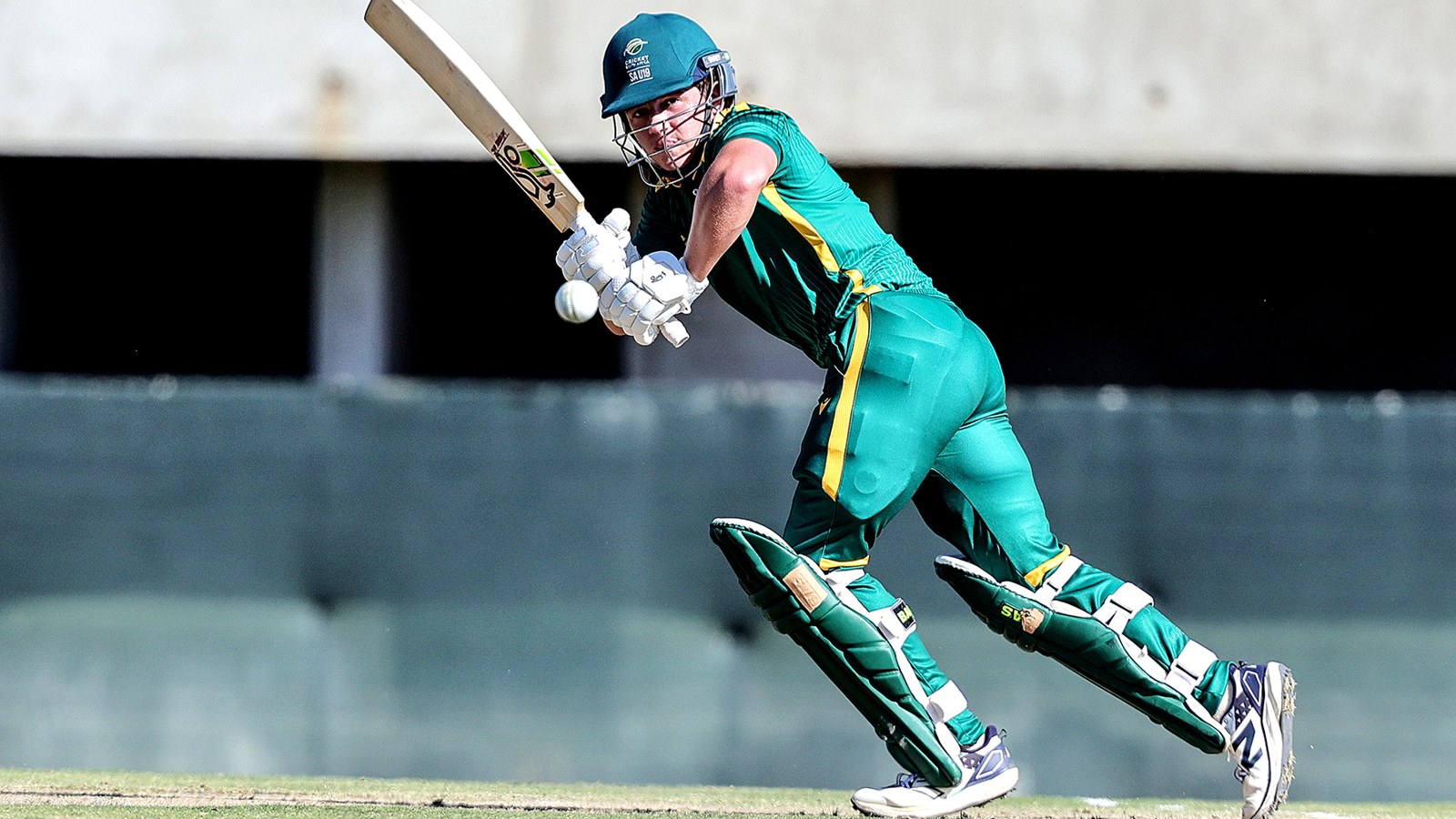 South African cricketer in green and gold playing a drive during a match