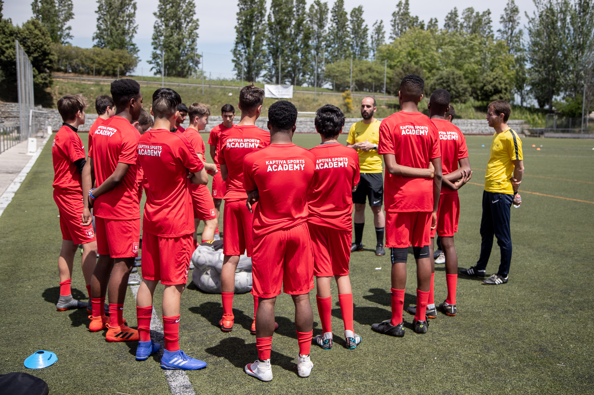 Young footballers in red and blue kit competing during a school football tour match on an artificial pitch at a Spanish academy