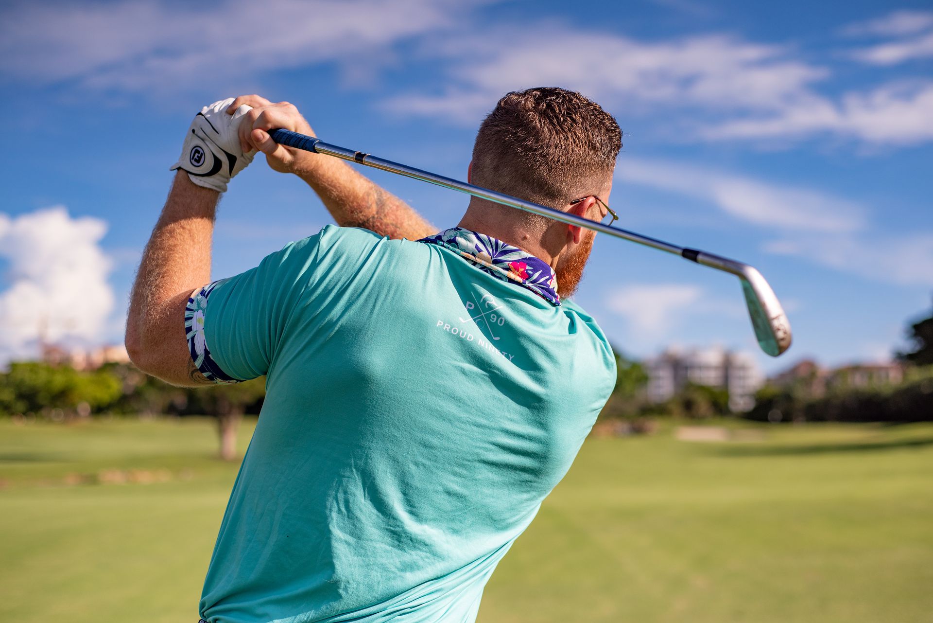 Golfer mid-swing on a sunlit palm-lined fairway at a luxury golf resort in Asia