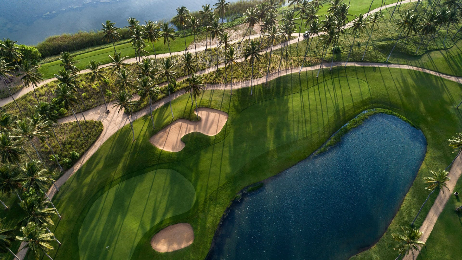 An aerial view of a lush palm-lined coastal golf course in Sri Lanka beside the ocean