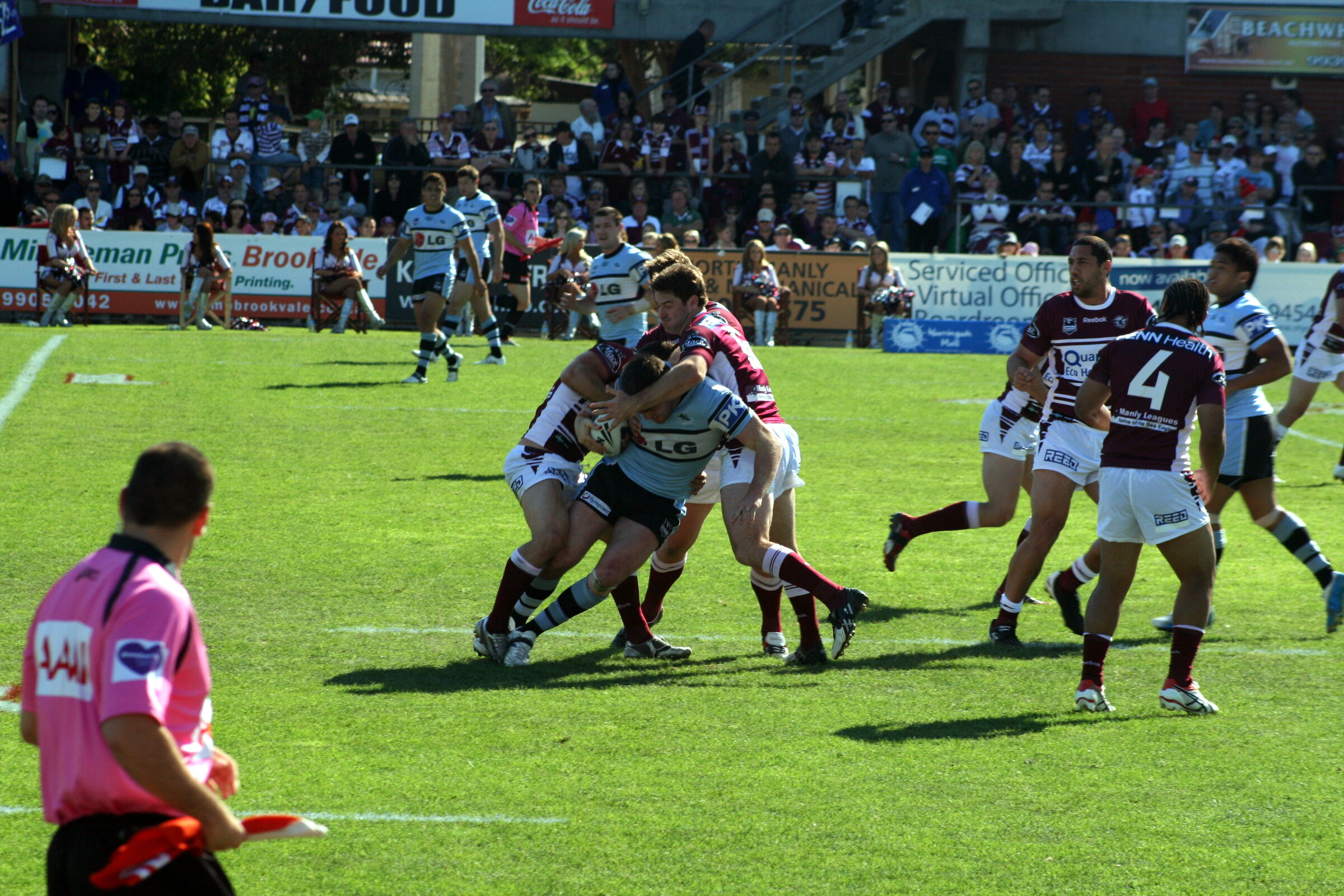 Rugby league players from opposing NRL teams in a tackle during a match