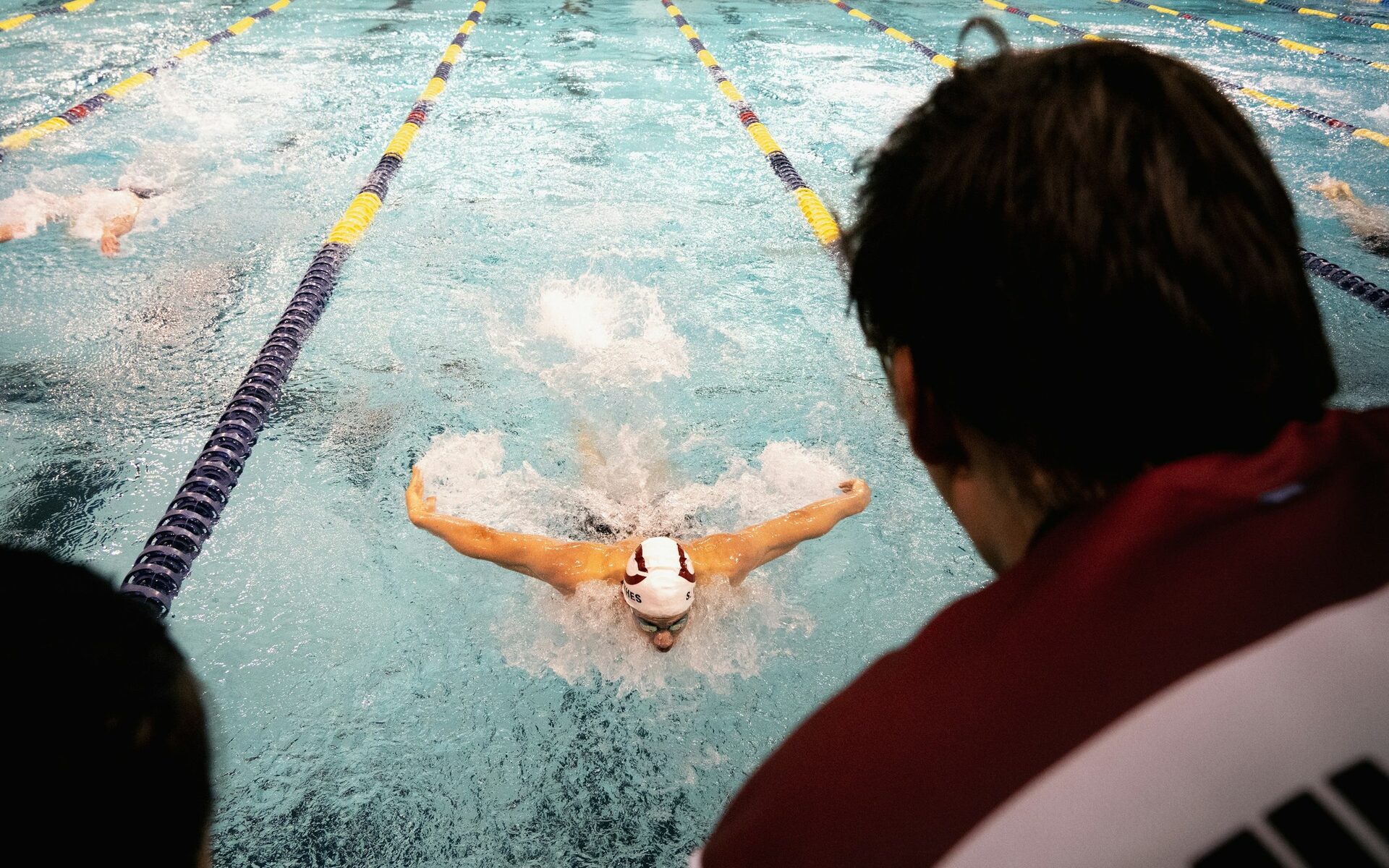 Coach watching a swimmer’s butterfly technique from the pool deck