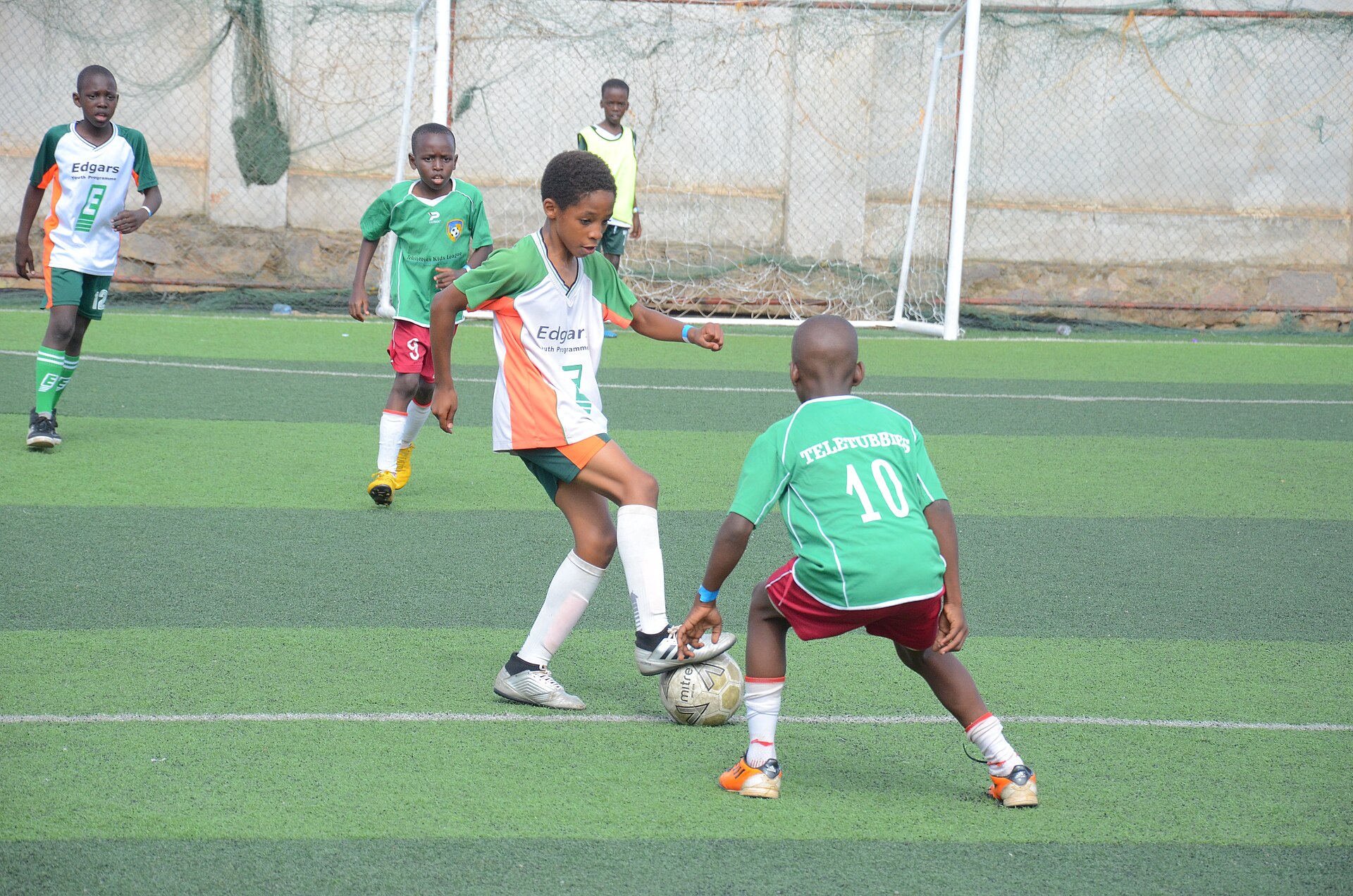 Young footballers competing for the ball during a youth tournament match on artificial turf